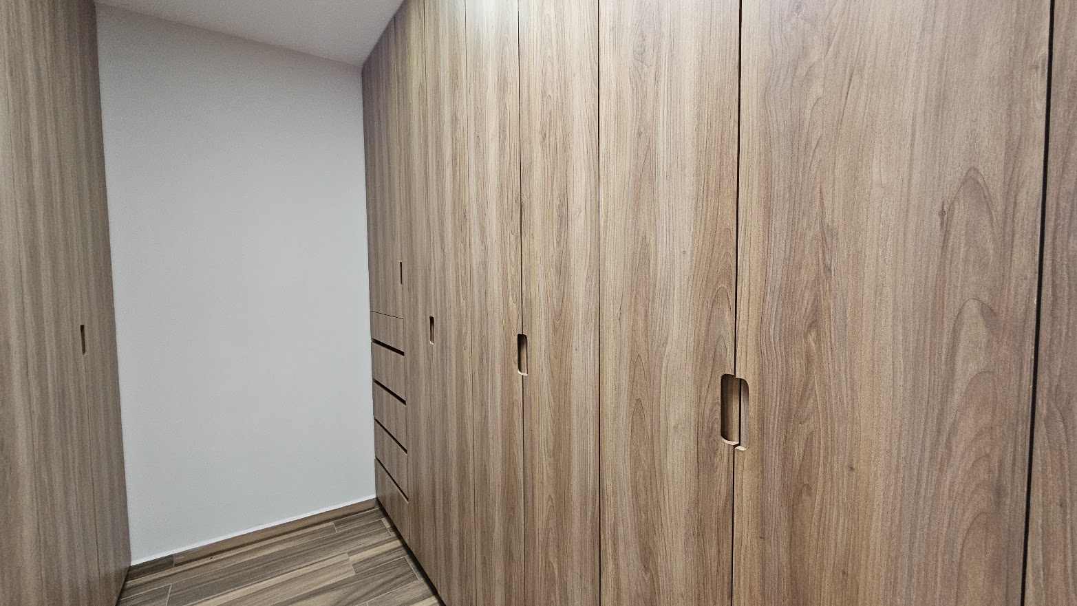 Vestidor con clósets de carpintería a medida en madera de piso a techo y cajonera integrada
